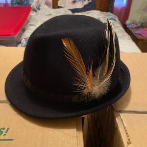 Black fedora hat with a brown feather on the side.